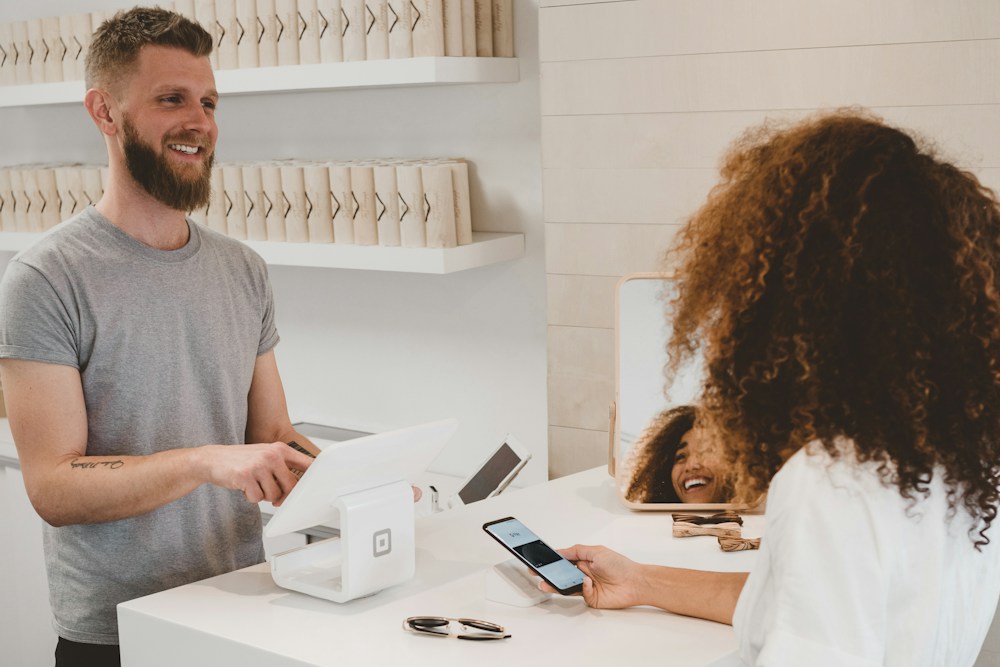 A customer pays with her phone at a shop counter
